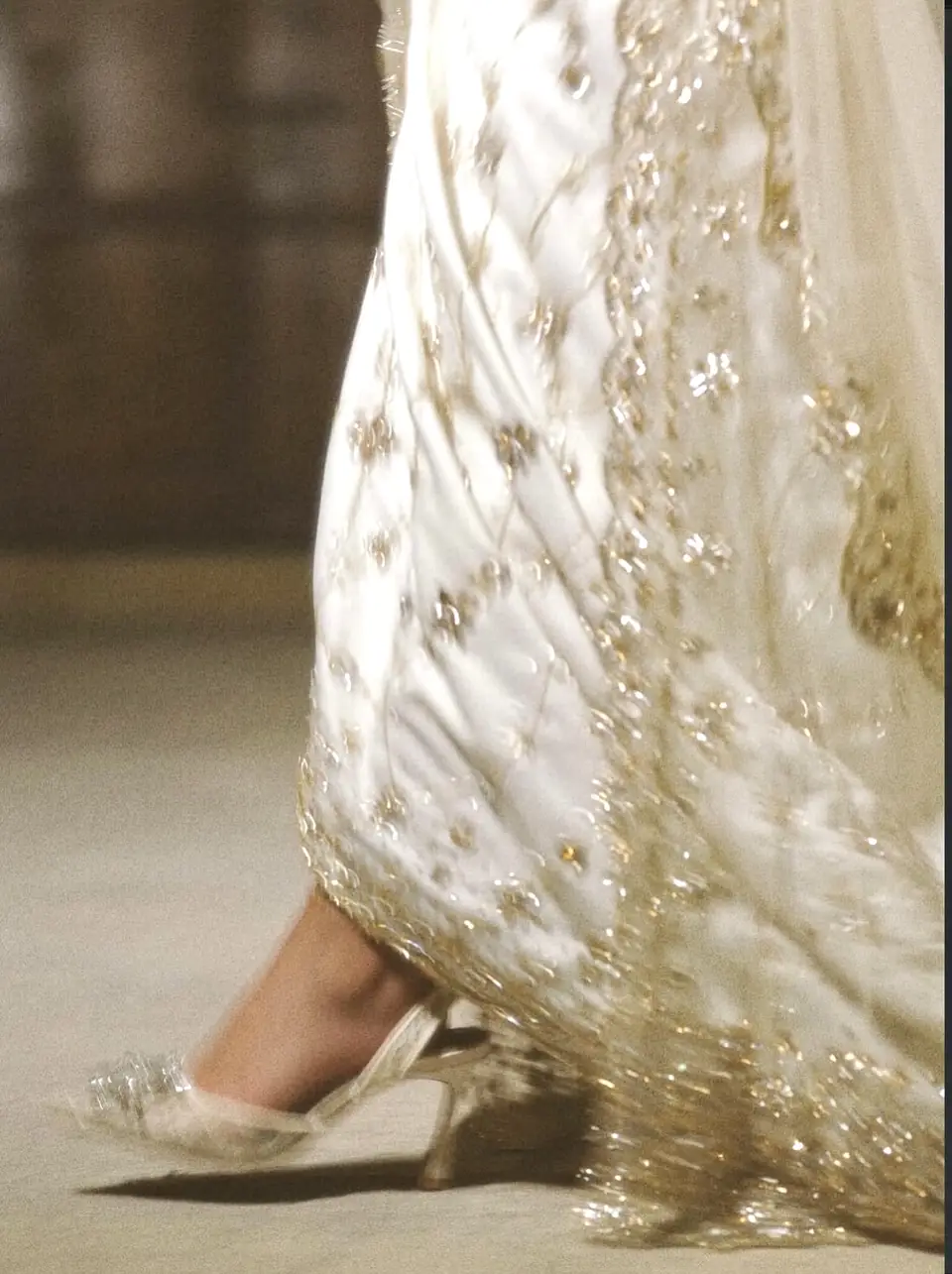 Gold-beaded hem of an ivory bridal gown in motion