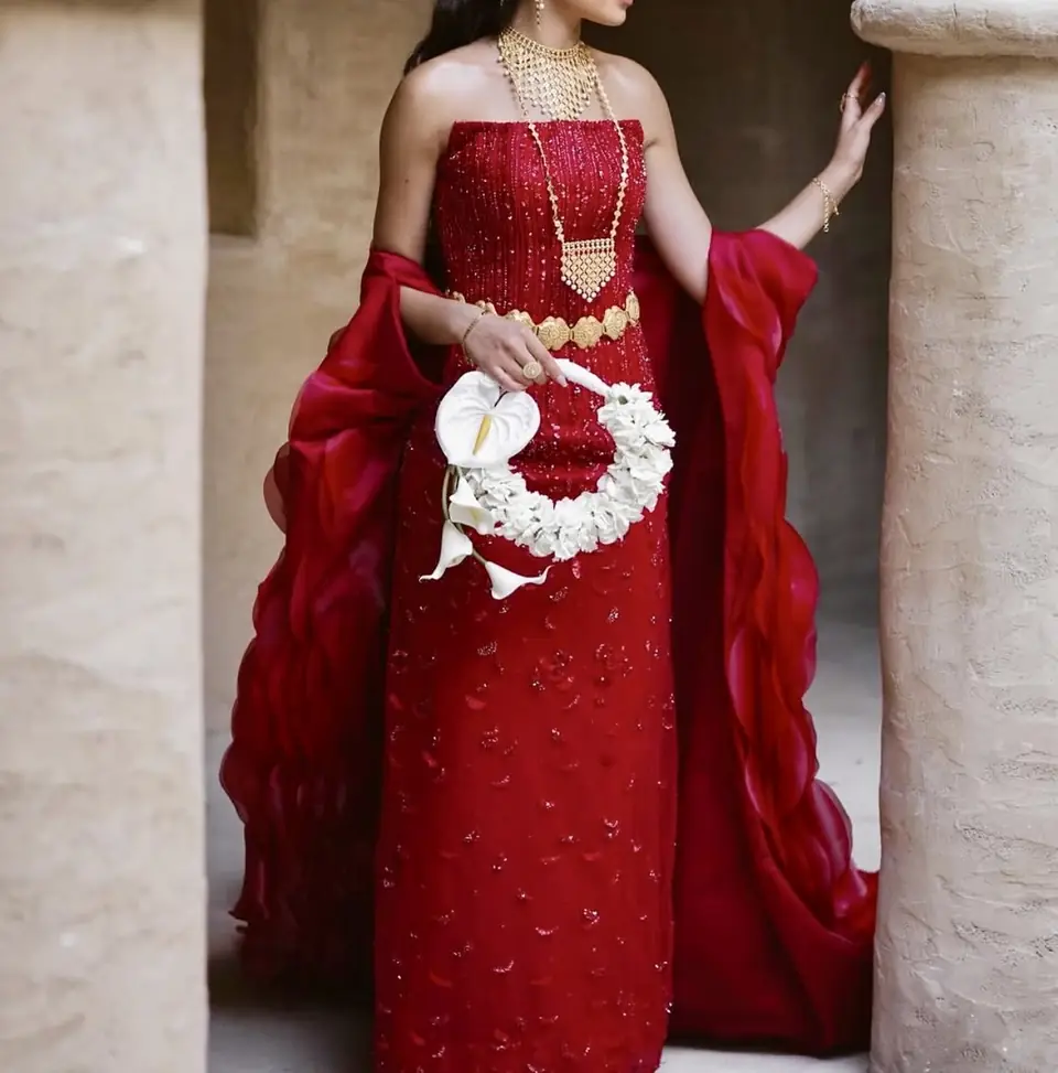 Red strapless beaded column gown with a sculpted organza petal cape
